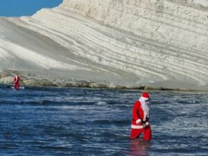 Babbo Natale cammina in acqua nel mare antistante Scala dei Turchi